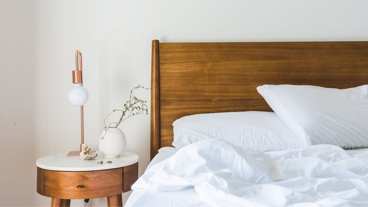 White Bedspread Beside Nightstand With White and Copper Table Lamp