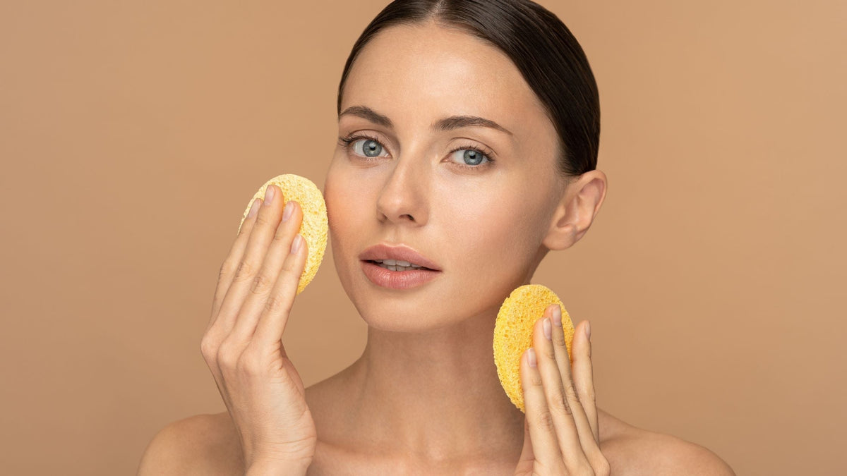 Young Woman Cleaning Face with Exfoliating Sponge 