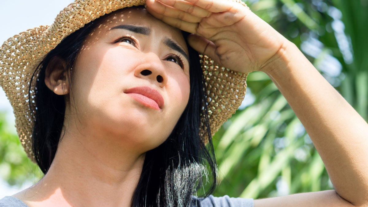 Asian Woman with Sunburned Face Standing Outdoors Under the Summer Sun