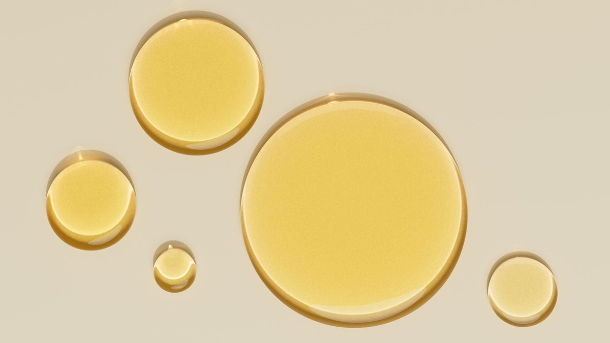 Circle drops of yellow tint retinol serum on background