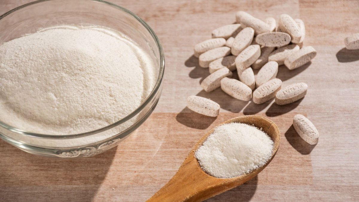 Collagen powder and pill supplements laid on wood surface
