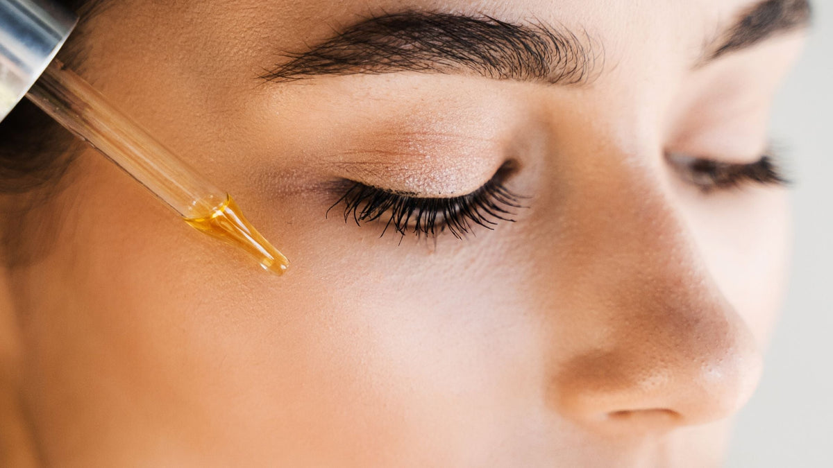Girl applying serum with pipette on face. Young woman with acid dropper is applying drops of acid on her skin