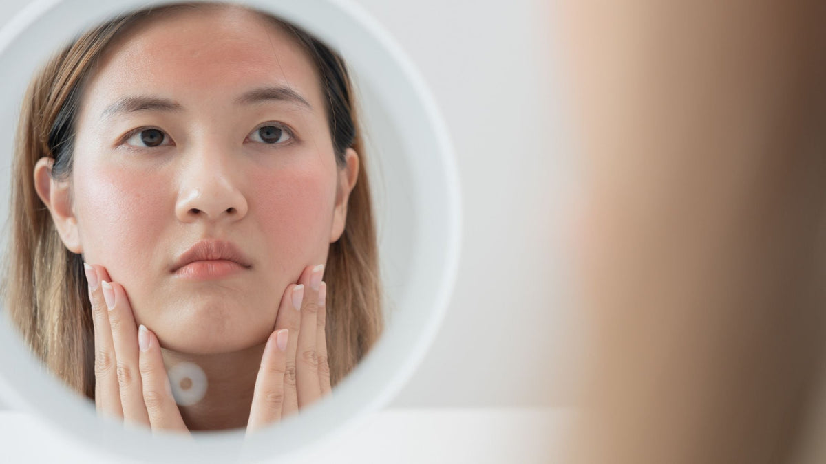 Woman touching sun damaged skin in mirror