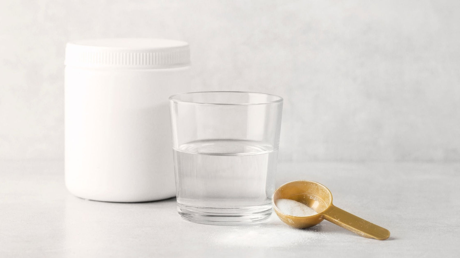 collagen powder on table with cup of water