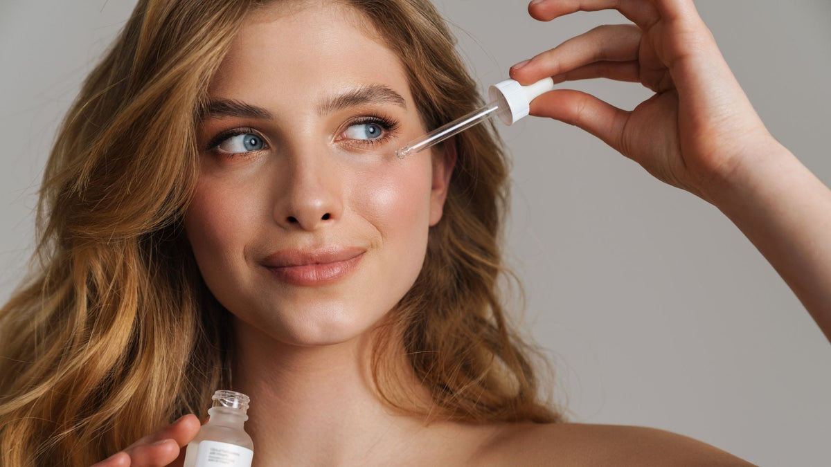 young woman applying serum on face with pipette